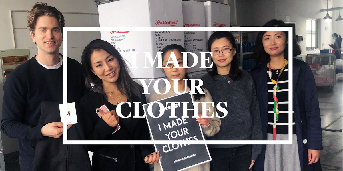 5 personer i et fabrikklokale holder opp en plakat som sier: I made your clothes