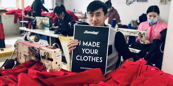 Mann i en tekstilfabrikk med en plakat med teksten: I made your clothes